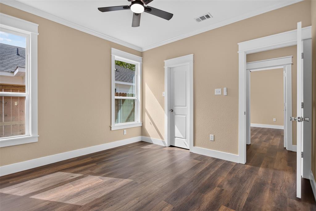 Wood-finish flooring, crisp white door and window casing, multi-pane windows, and a ceiling fan with integrated light fixture