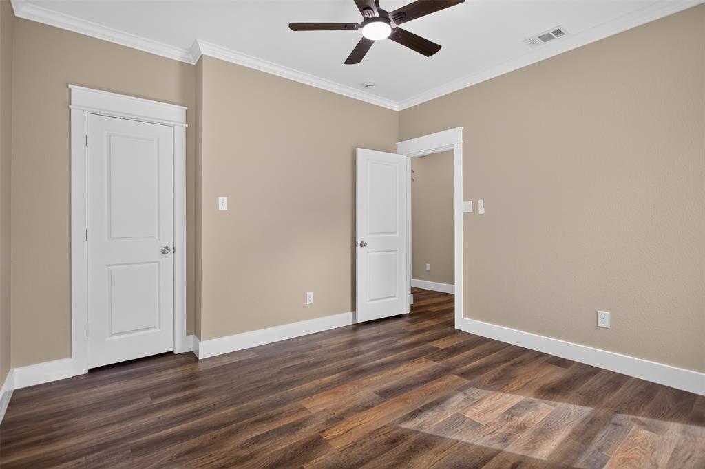 Room featuring wood-finish flooring, crown molding, two-panel interior doors with white trim, and a ceiling fan
