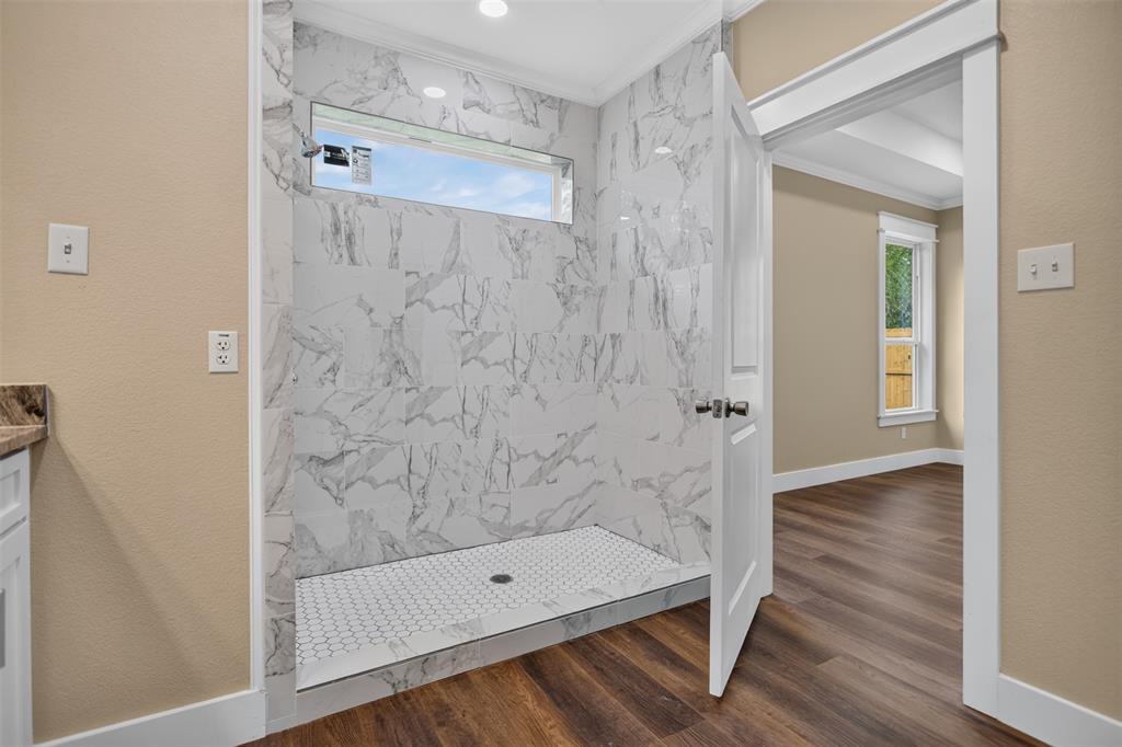 Walk-in shower with floor-to-ceiling veined stone-look tile, transom window, and hexagonal mosaic tile flooring