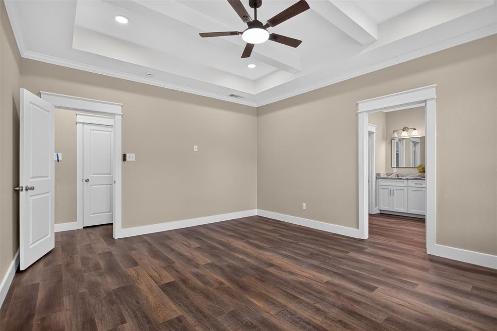Tray ceiling with recessed lighting and a central ceiling fan, wood-finish flooring, and white paneled interior doors