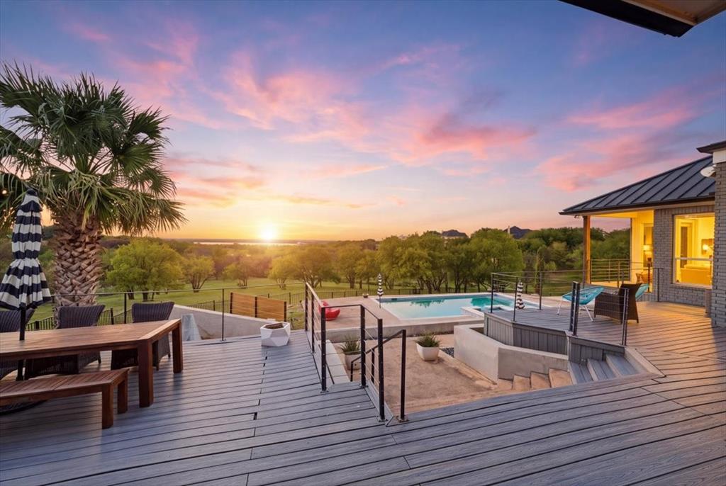 Multi-level deck with horizontal railing, built-in swimming pool, landscape backdrop, and metal roof overhang