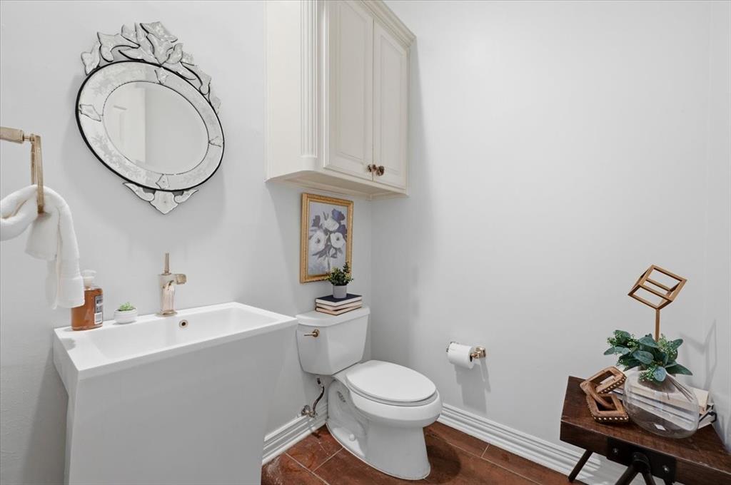 Wall-mounted cabinetry, pedestal sink with a metallic faucet, ornate wall mirror, and tile flooring