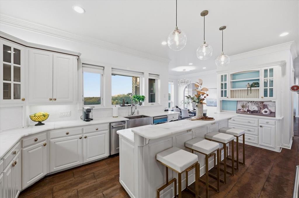 Kitchen featuring white cabinetry, stone countertops, a stainless steel undermount sink, wood-finish flooring, and glass pendant lighting