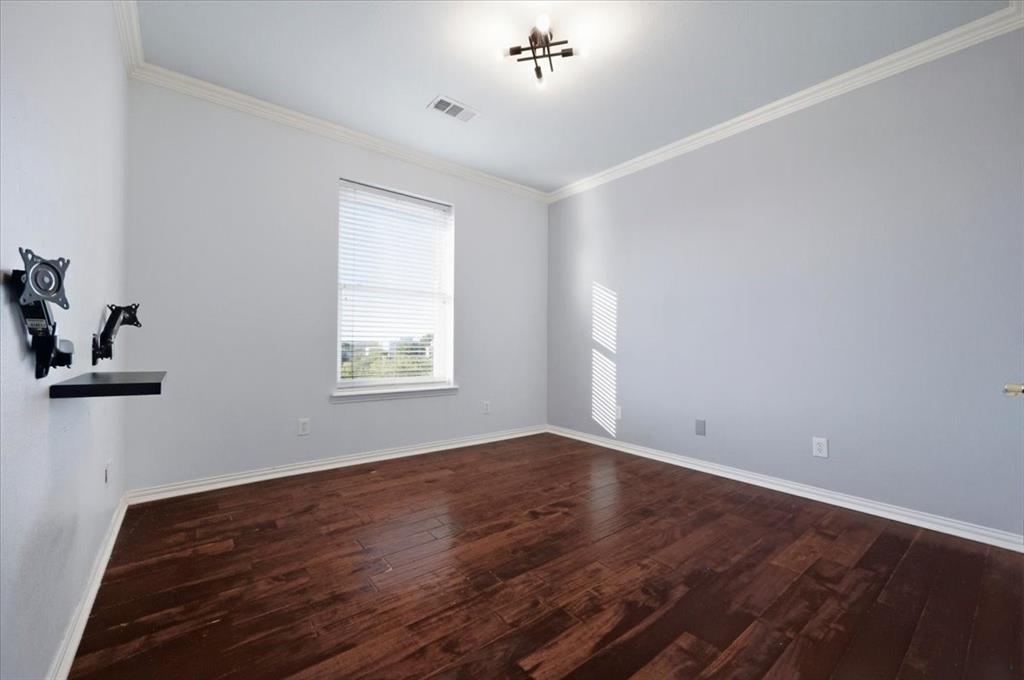 Room featuring dark wood-finish flooring, neutral wall tones, crown molding, and a central multi-light fixture