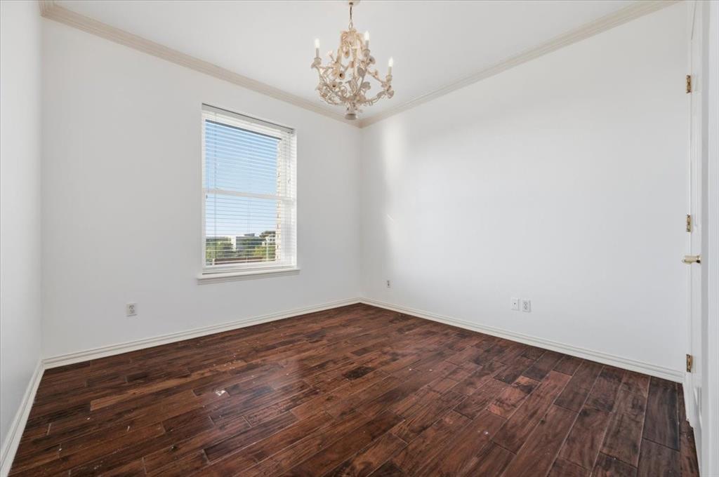 Room featuring wood-finish flooring, crown molding, and an ornate chandelier