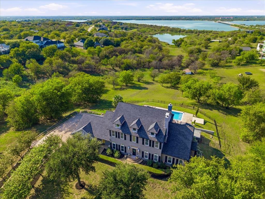Multi-story residence featuring a shingled roof, dormer windows, shuttered exterior detailing, and a backyard swimming pool set on a sprawling parcel with mature trees