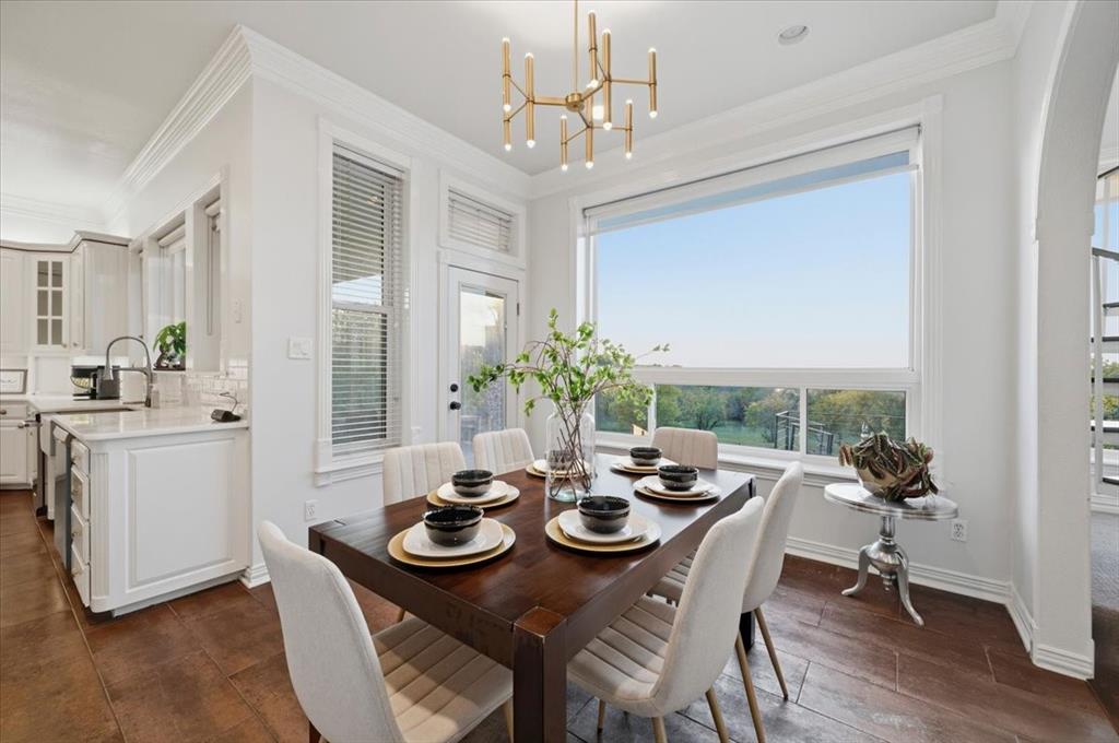 Dining area featuring wood-finish flooring, a contemporary multi-arm brass chandelier, crown molding, and a large picture window