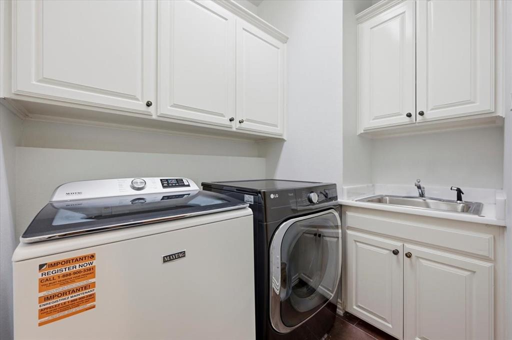 Dedicated laundry area featuring white shaker-style cabinetry, a drop-in stainless steel sink, and solid-surface countertops