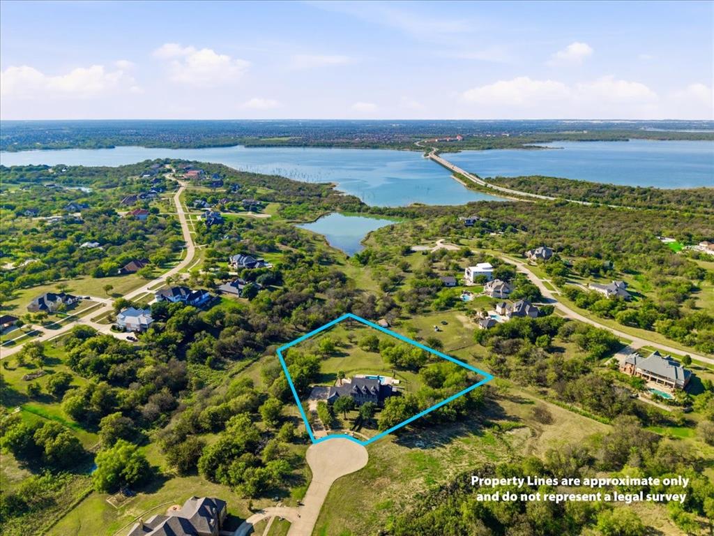 Aerial view of expansive residential lot featuring mature trees, a private swimming pool, and proximity to lakefront shoreline