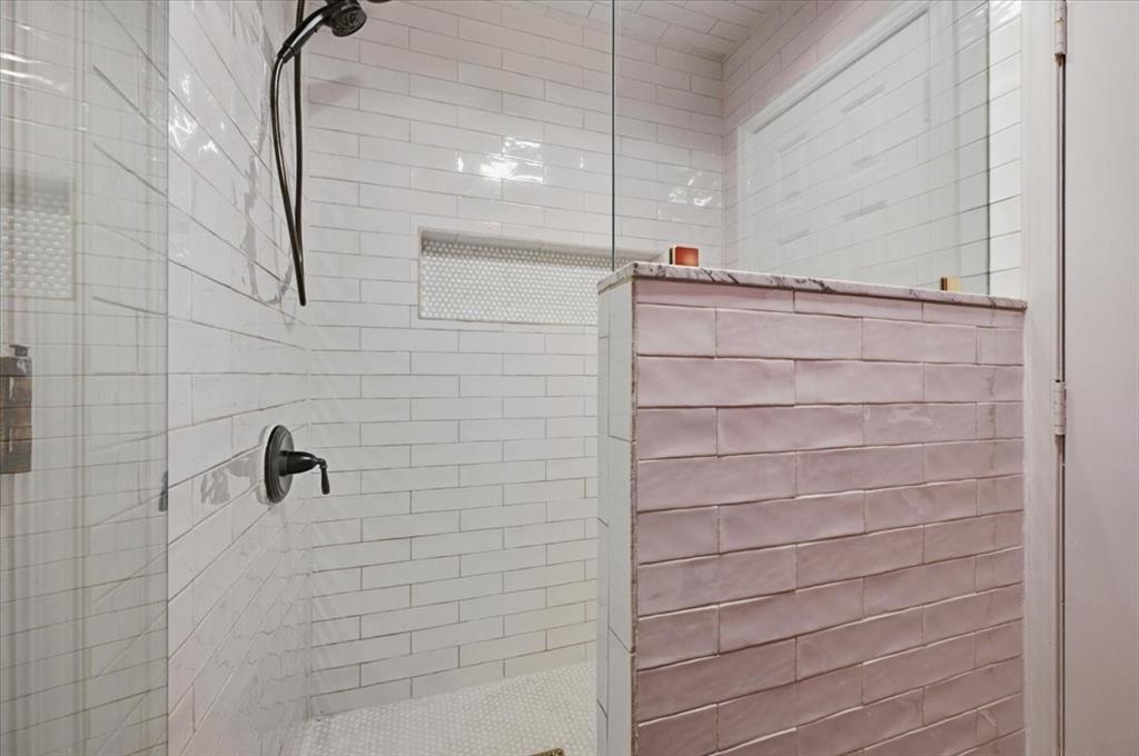Walk-in shower featuring subway tile wall finishes, a built-in recessed niche, a glass partition, and a matte black shower fixture