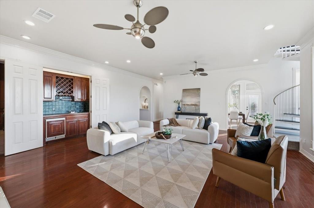 Living area featuring wood-finish flooring, recessed lighting, built-in cabinetry with integrated wine storage, arched doorways, and a spiral staircase