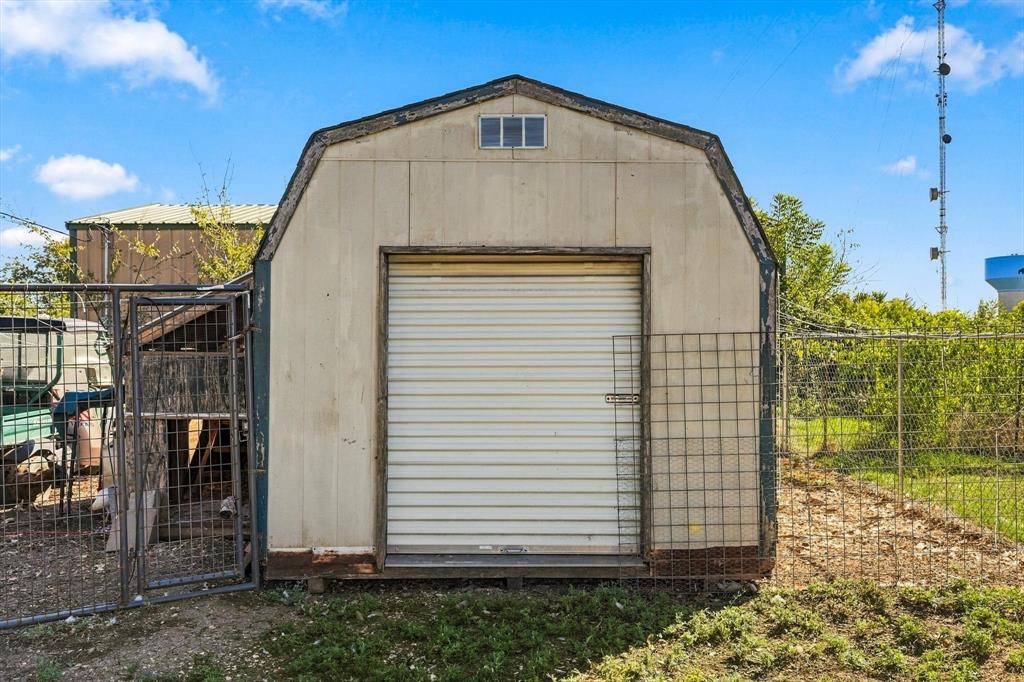12 x 10 Outbuilding featuring a gambrel roof design, a roll-up metal door, and exterior metal wire fencing