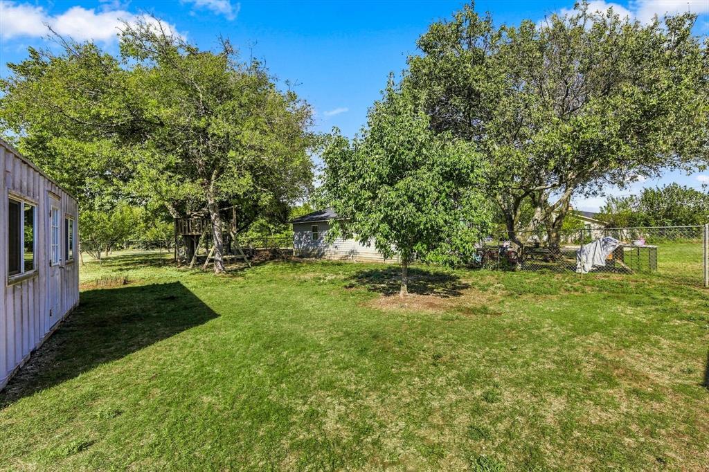 Expansive backyard featuring mature trees, chain-link perimeter fencing.