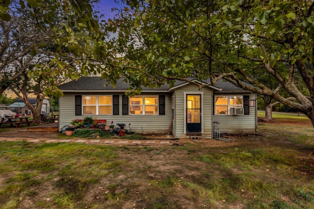Single-story residence featuring horizontal siding, decorative shutters, a covered entryway, and mature tree canopy Single-story residence featuring horizontal siding, decorative shutters, a covered entryway, and mature tree canopy