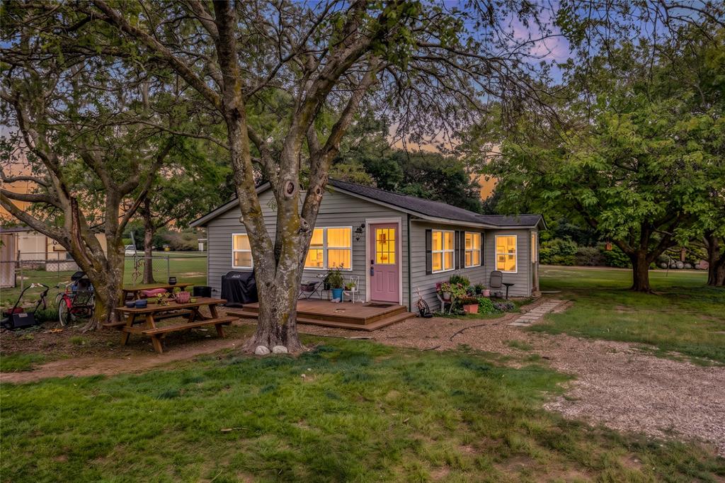 Single-story residence featuring light gray horizontal siding, a wooden front deck, and multiple windows with exterior shutters Single-story residence featuring light gray horizontal siding, a wooden front deck, and multiple windows with exterior shutters