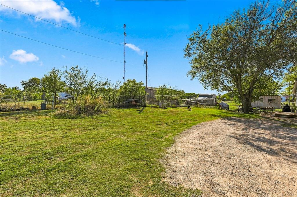 Expansive grounds featuring a gravel driveway, open green space, mature trees, and perimeter fencing Expansive grounds featuring a gravel driveway, open green space, mature trees, and perimeter fencing
