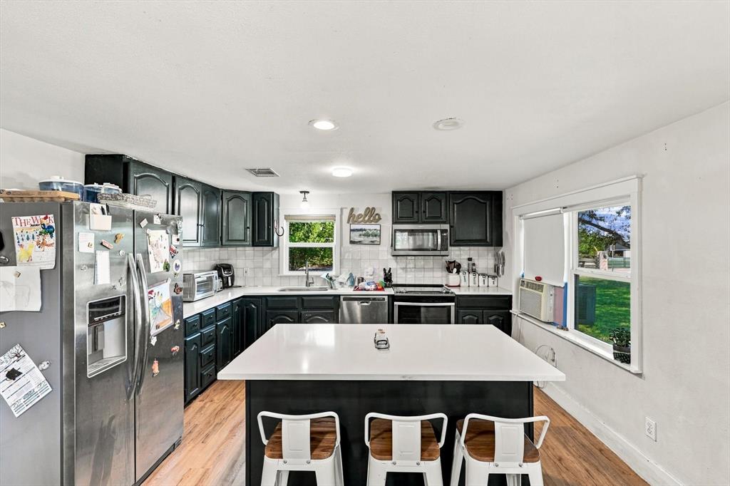 Kitchen featuring dark-finish cabinetry, central island with a white countertop, recessed lighting, and wood-finish flooring