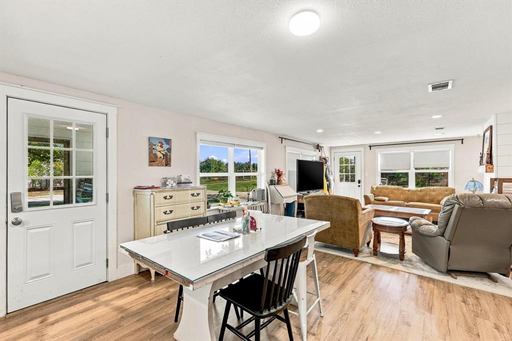 Open-concept interior featuring wood-finish flooring, multi-pane glass entry doors, recessed lighting, and large windows Open-concept interior featuring wood-finish flooring, multi-pane glass entry doors, recessed lighting, and large windows