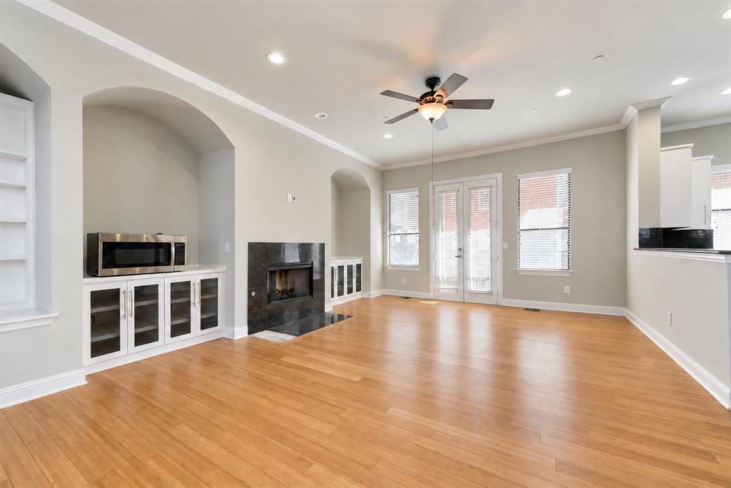 Hardwood-finish flooring, built-in shelving, fireplace with dark stone surround, recessed lighting, and ceiling fan