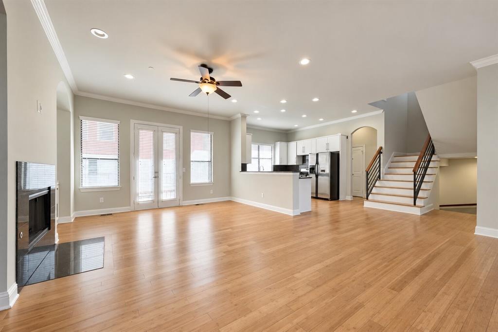 Light wood-finish flooring throughout, recessed lighting, and a modern fireplace with a black surround