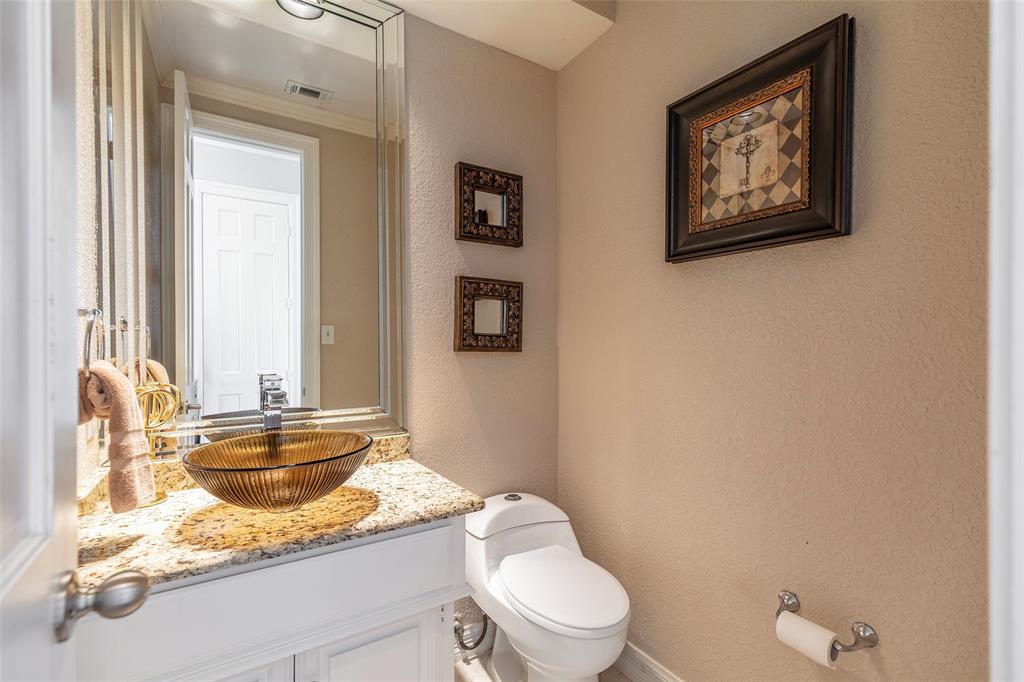 A glass vessel sink, granite countertop and beveled mirror add character to the separate powder bath.