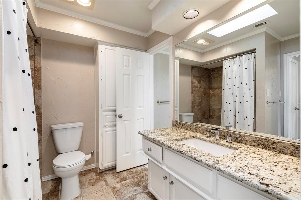 Jack and Jill bath features a granite vanity, white cabinetry and a tiled tub-and-shower combination.