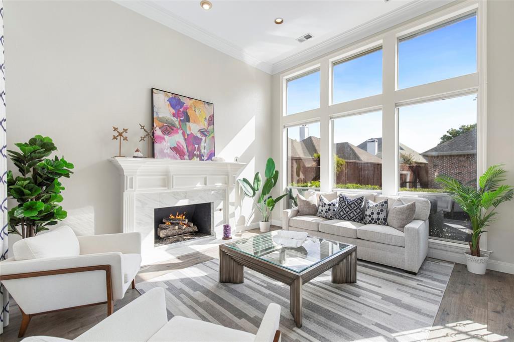 Tall windows bring abundant natural light into the front living room, where a fireplace anchors a comfortable space for conversation.