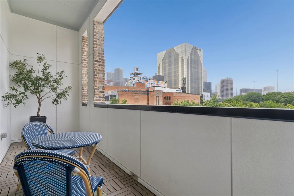 Private balcony off the main living area offers views of the Dallas skyline. Image of model home with similar layout.