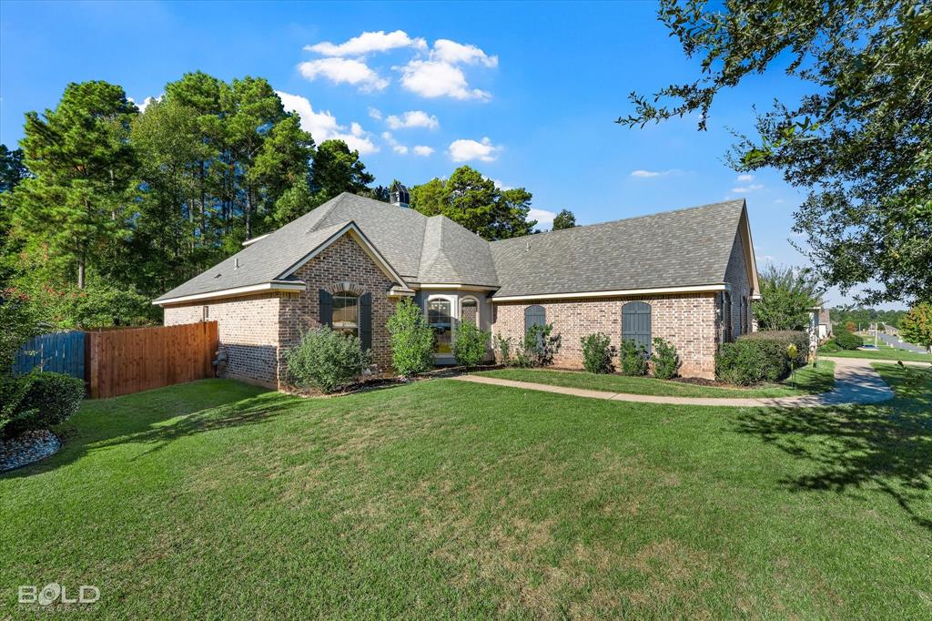 Brick exterior featuring a multi-gabled roofline, arched window detailing, decorative shutters, and a concrete walkway