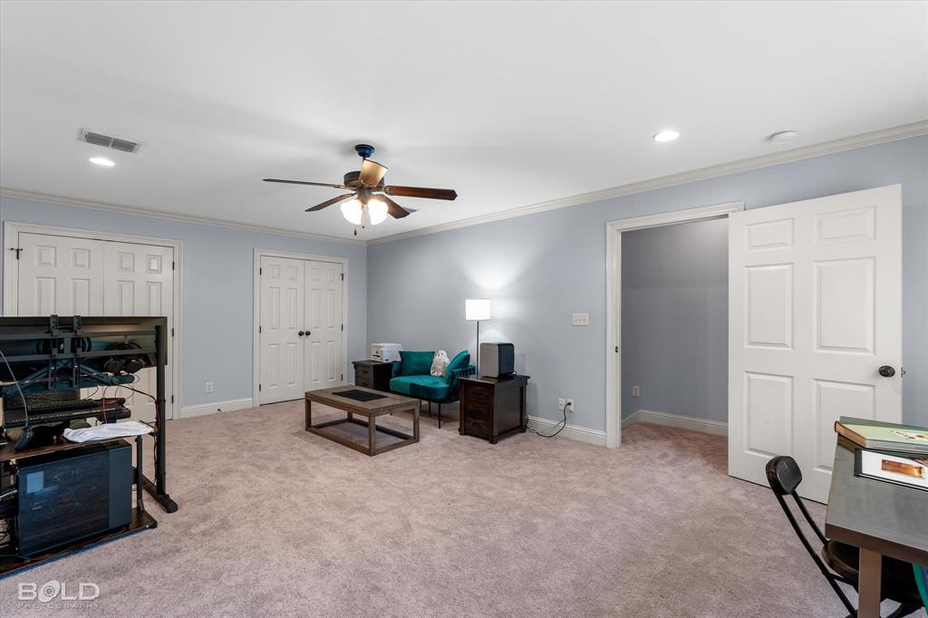 Spacious interior featuring neutral carpeting, recessed lighting, a ceiling fan with integrated light fixture, and multiple sets of white panel doors