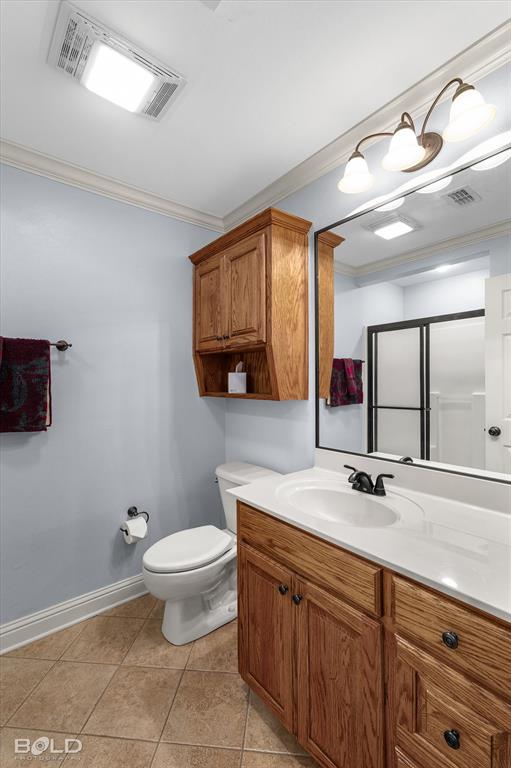 Bathroom featuring a vanity with wood cabinetry, white countertop, and dark-finish hardware, paired with a matching wall-mounted cabinet, tile flooring, and a large mirror with integrated lighting