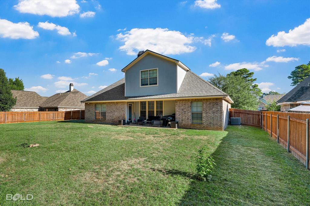 Backyard featuring a grass lawn, a covered concrete patio, and a wood privacy fence