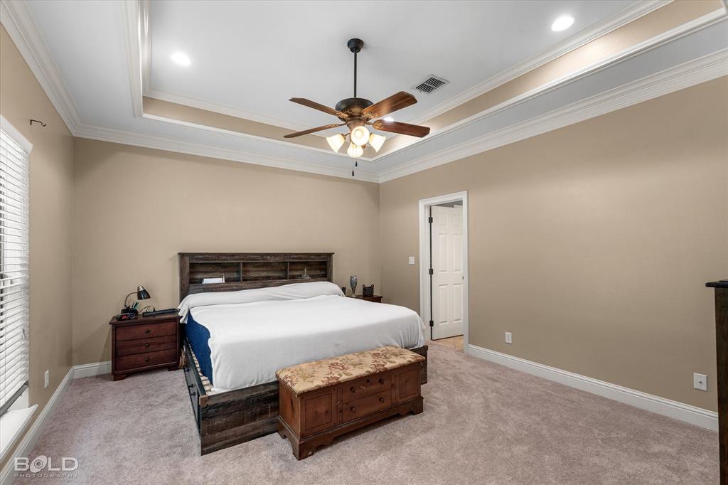 Tray ceiling with crown molding, recessed lighting, and a central ceiling fan