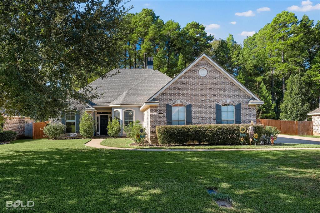 Single-story brick exterior featuring a multi-gabled roofline, arched window detailing, exterior shutters, and a front-facing chimney