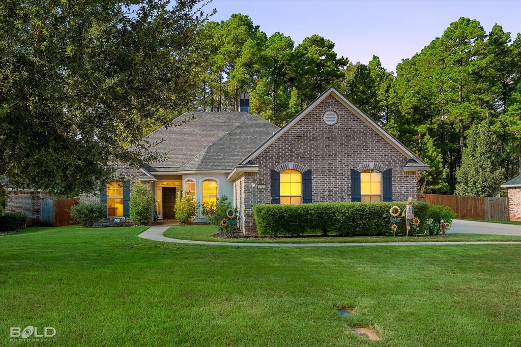 Brick exterior featuring arched windows, dark decorative shutters, a multi-gabled roofline, and a concrete walkway