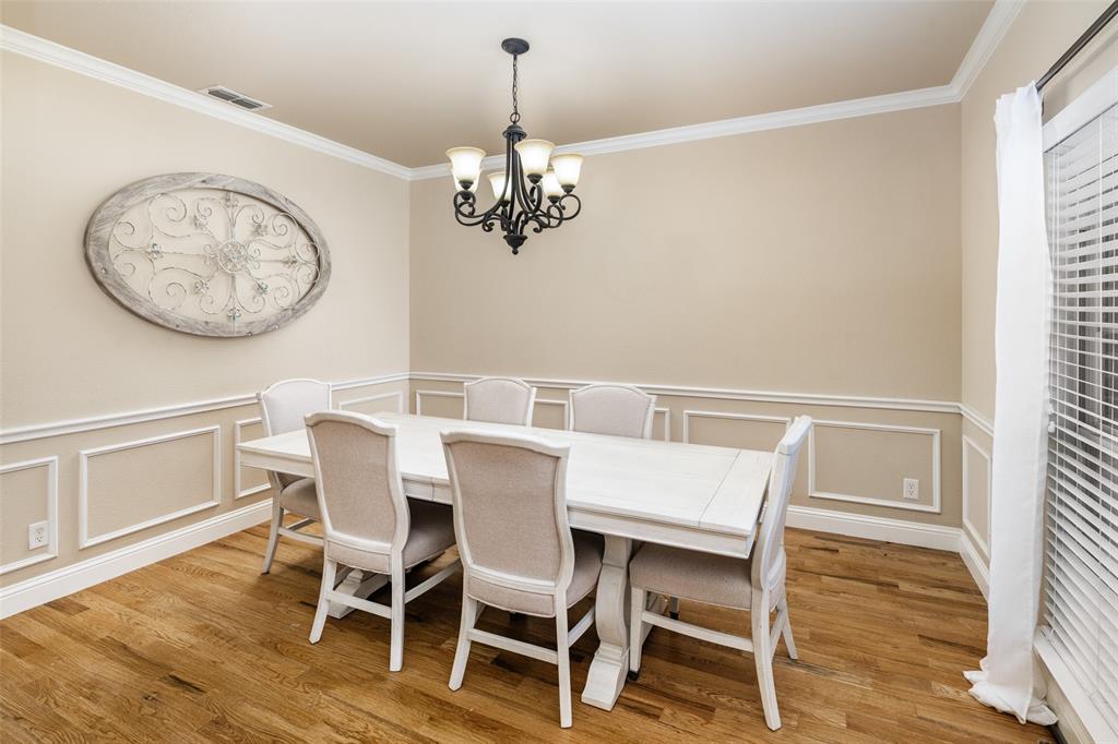 Dining area featuring wood-finish flooring, decorative wall wainscoting, and a five-light traditional chandelier