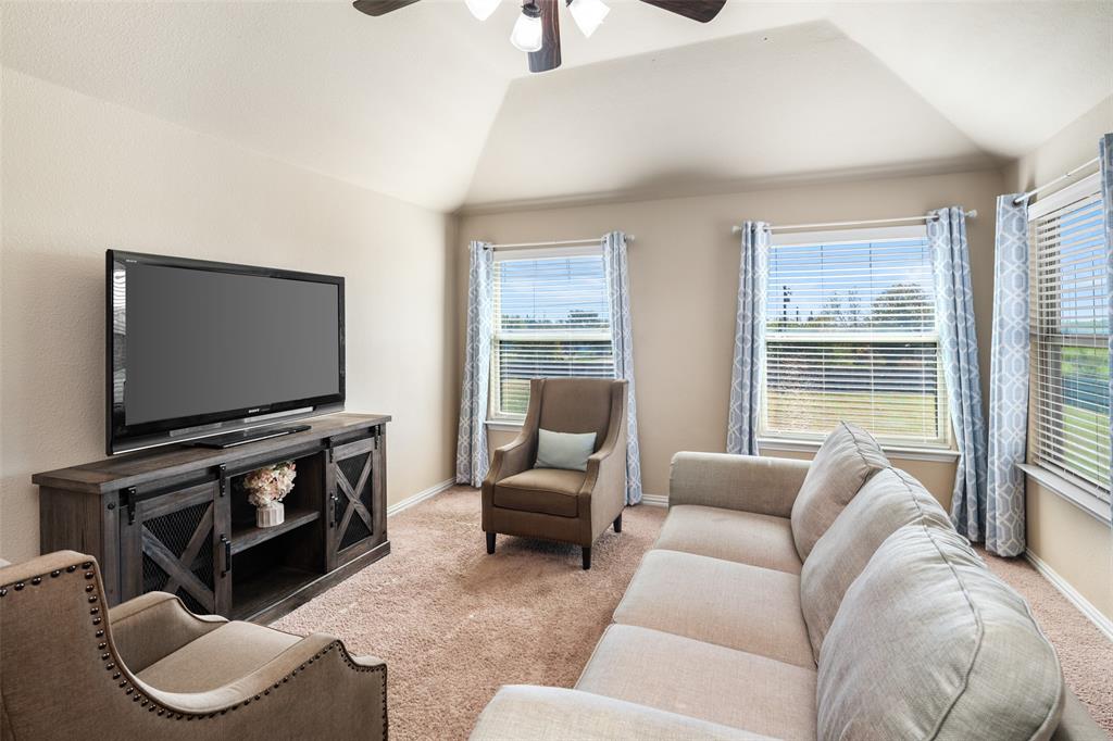 Vaulted ceiling, ceiling fan with light fixture, and multiple windows with horizontal blinds