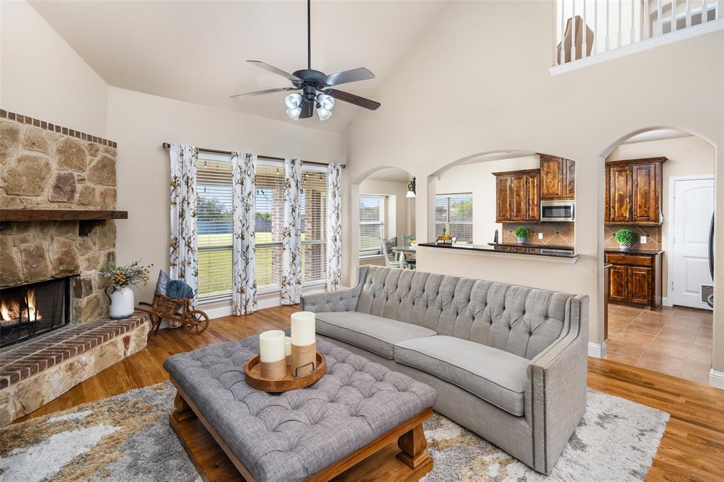 Vaulted ceilings, floor-to-ceiling stone fireplace with a timber mantel, wood-finish flooring, and arched architectural openings Vaulted ceilings, floor-to-ceiling stone fireplace with a timber mantel, wood-finish flooring, and arched architectural openings