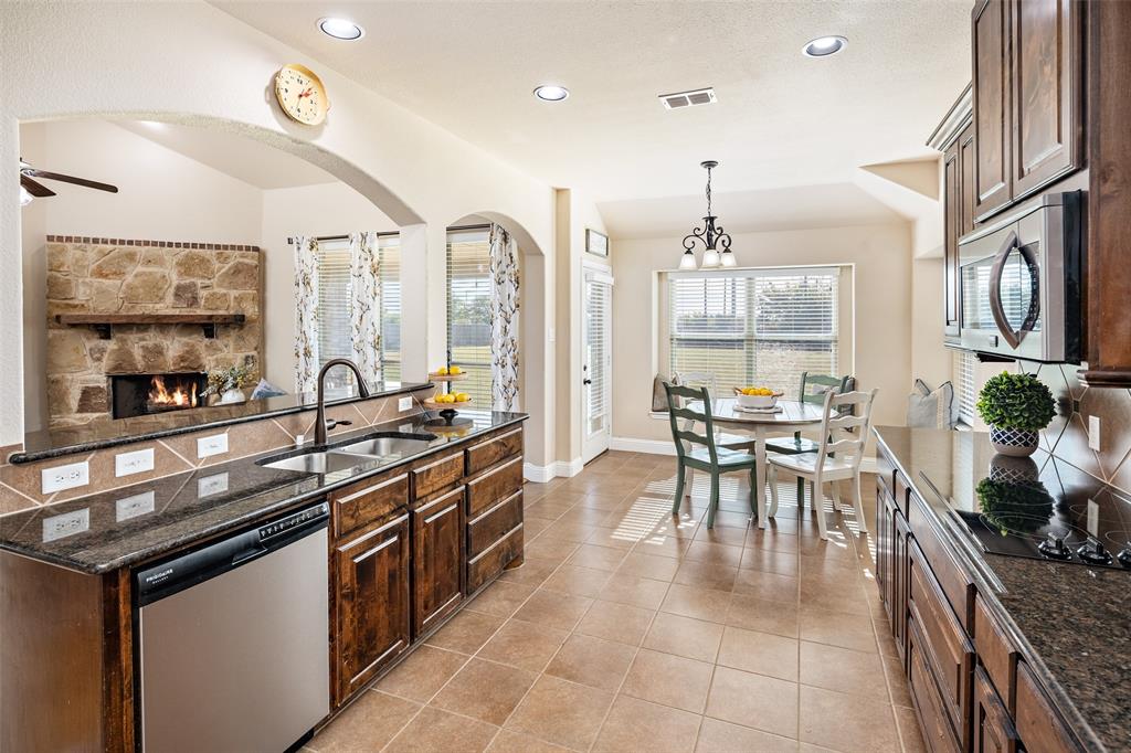 Kitchen featuring dark-finish cabinetry, stone countertops, recessed lighting, tile flooring, and a stone-accented fireplace Kitchen featuring dark-finish cabinetry, stone countertops, recessed lighting, tile flooring, and a stone-accented fireplace