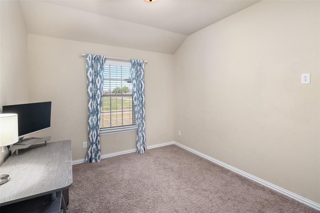 Room featuring neutral-toned carpeting, vaulted ceilings, and a window with blinds