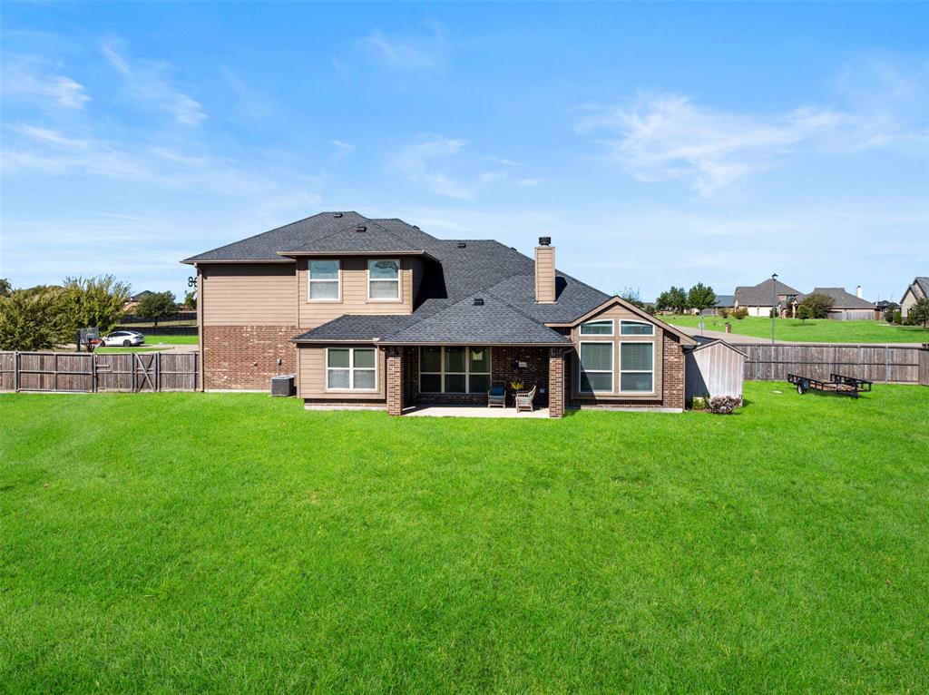 Two-story residence featuring a brick and siding exterior, asphalt shingle roof, rear covered patio, and fenced-in backyard