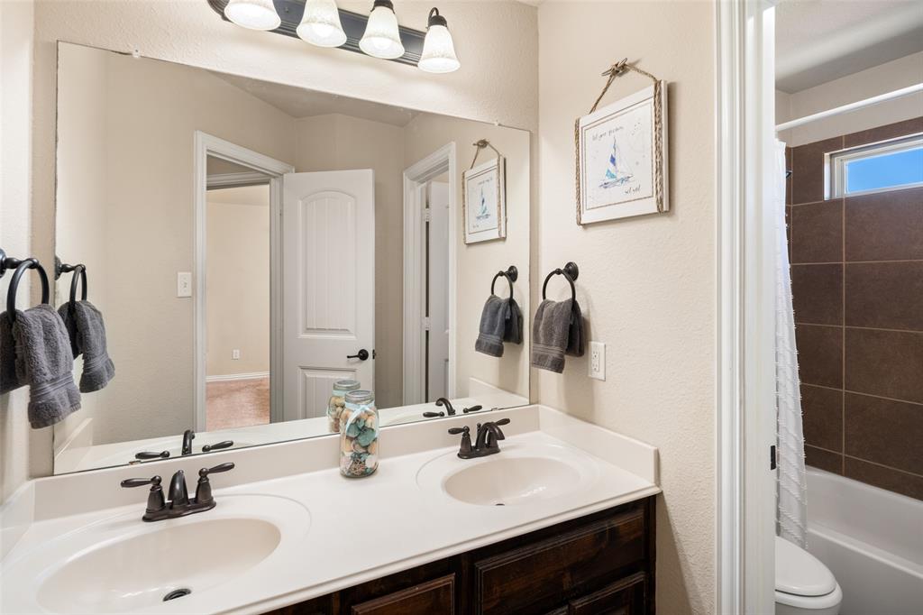 Double vanity featuring dark wood-finish cabinetry, solid-surface countertop with integrated dual sinks, oil-rubbed bronze fixtures, and large rectangular wall mirror