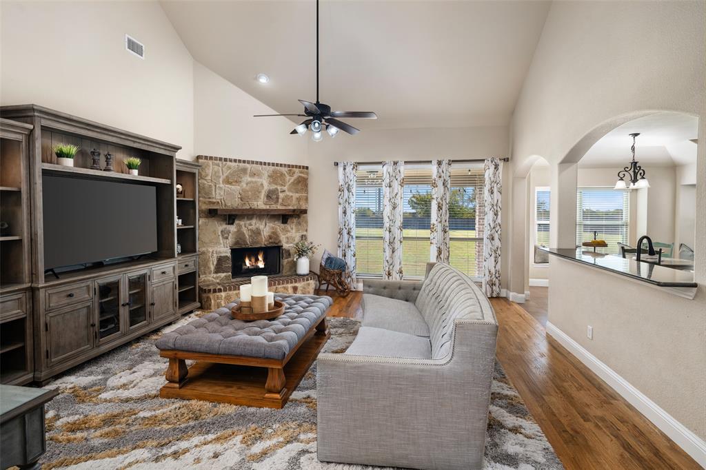 Vaulted ceilings with a stone-surround fireplace, built-in cabinetry, wood-finish flooring, and a breakfast bar with an arched pass-through Vaulted ceilings with a stone-surround fireplace, built-in cabinetry, wood-finish flooring, and a breakfast bar with an arched pass-through