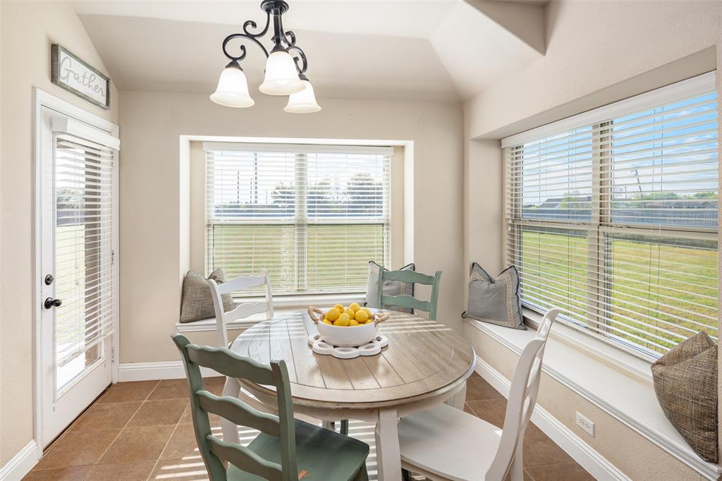 Sun-drenched breakfast area featuring built-in window seating, tile flooring, tray ceiling, and a multi-arm chandelier