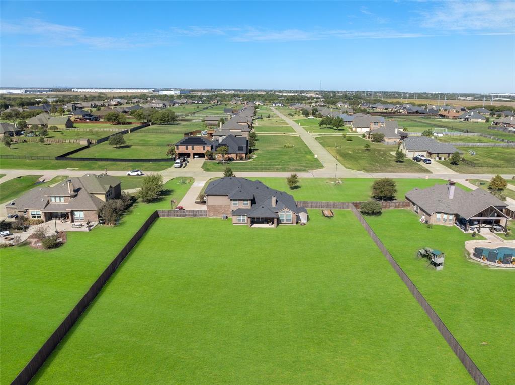 Aerial perspective featuring an expansive fenced backyard with a sprawling lawn and a covered rear patio Aerial perspective featuring an expansive fenced backyard with a sprawling lawn and a covered rear patio