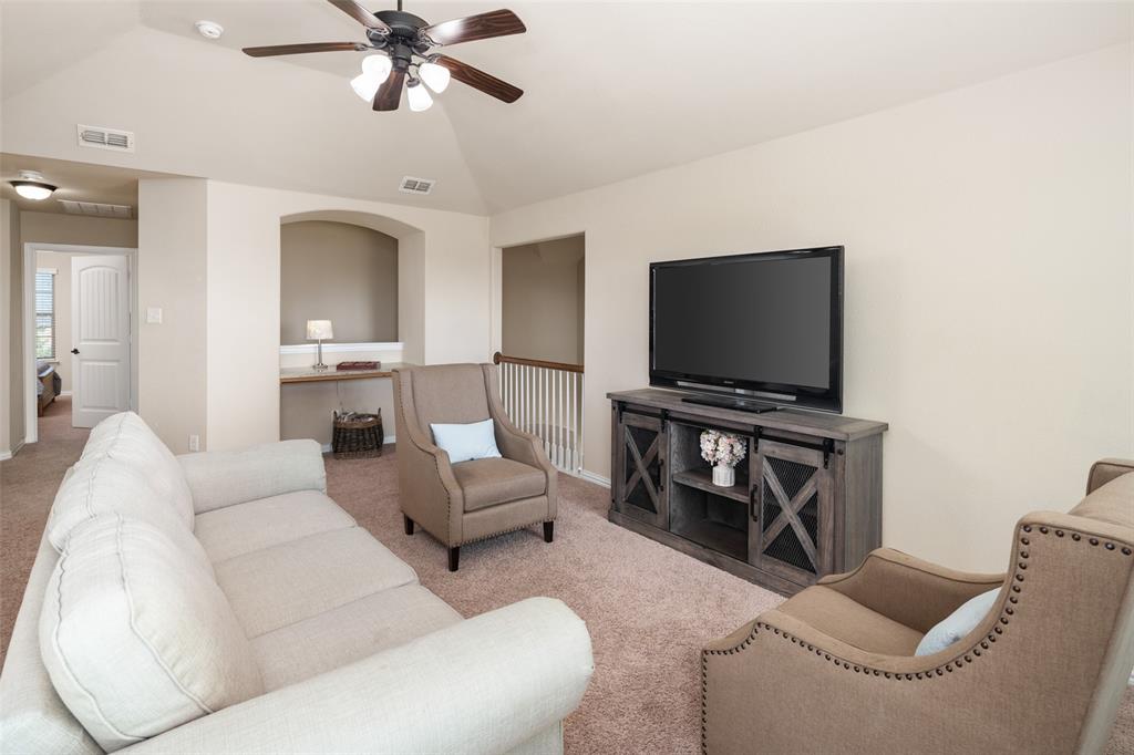 Vaulted ceiling featuring a central lighted ceiling fan, carpeted flooring, and a built-in recessed wall niche