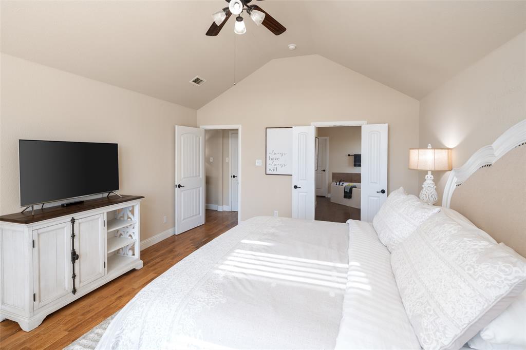Vaulted ceiling with an integrated multi-light ceiling fan and wood-finish flooring