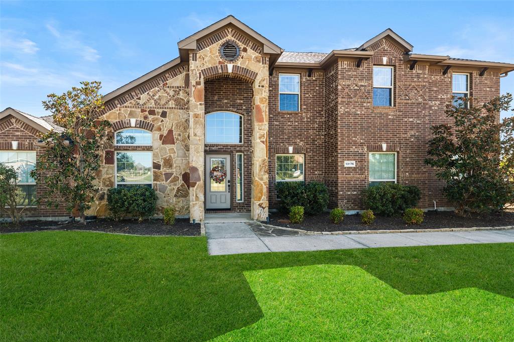 Two-story exterior featuring multi-tonal brick and stone veneer, arched windows, a recessed front entry with a decorative arched transom, and an expansive lawn Two-story exterior featuring multi-tonal brick and stone veneer, arched windows, a recessed front entry with a decorative arched transom, and an expansive lawn