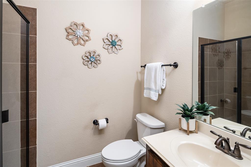 Bathroom featuring a vanity with an integrated countertop sink, dark finish faucet hardware, a large wall-mounted mirror, and a walk-in shower with tiled surround and black frame