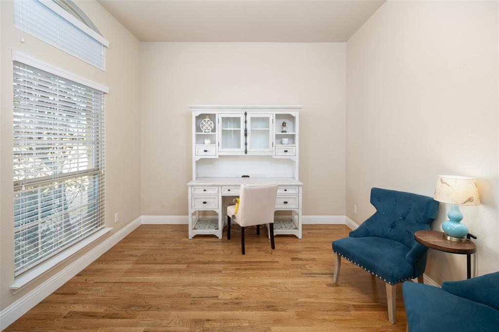 Room featuring wood-finish flooring, high ceilings, large windows with horizontal blinds, and an arched transom window